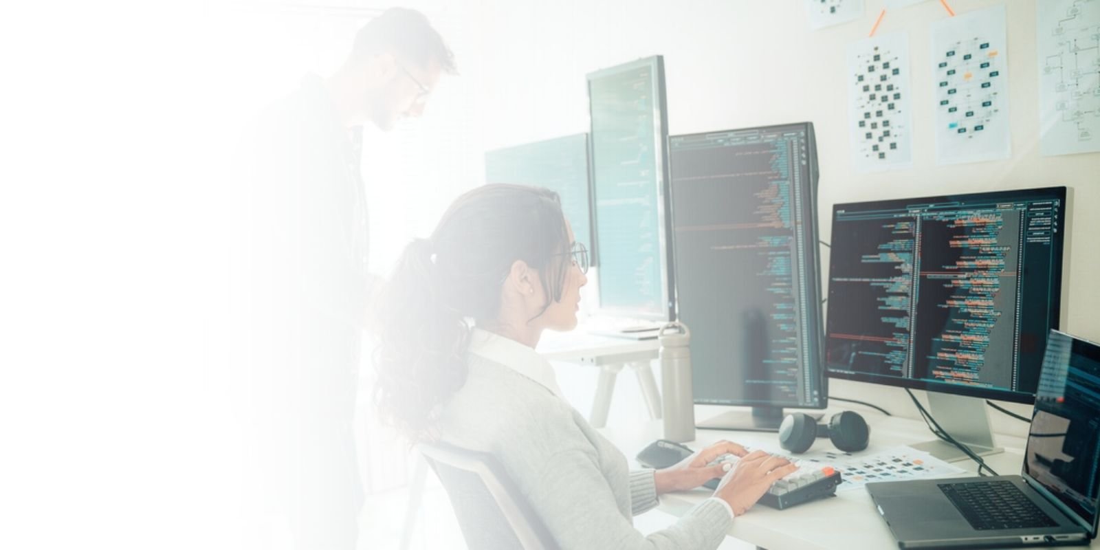 Dos ingenieros de software trabajando en un centro de desarrollo con múltiples monitores que muestran código de programación, simbolizando la evaluación técnica de perfiles de TI.