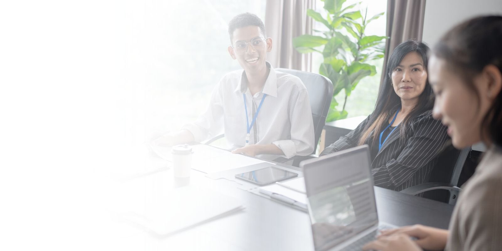 Reclutadora profesional de Talentium sonriendo y tomando notas, con una laptop que muestra una lista de perfiles de candidatos de alto nivel.