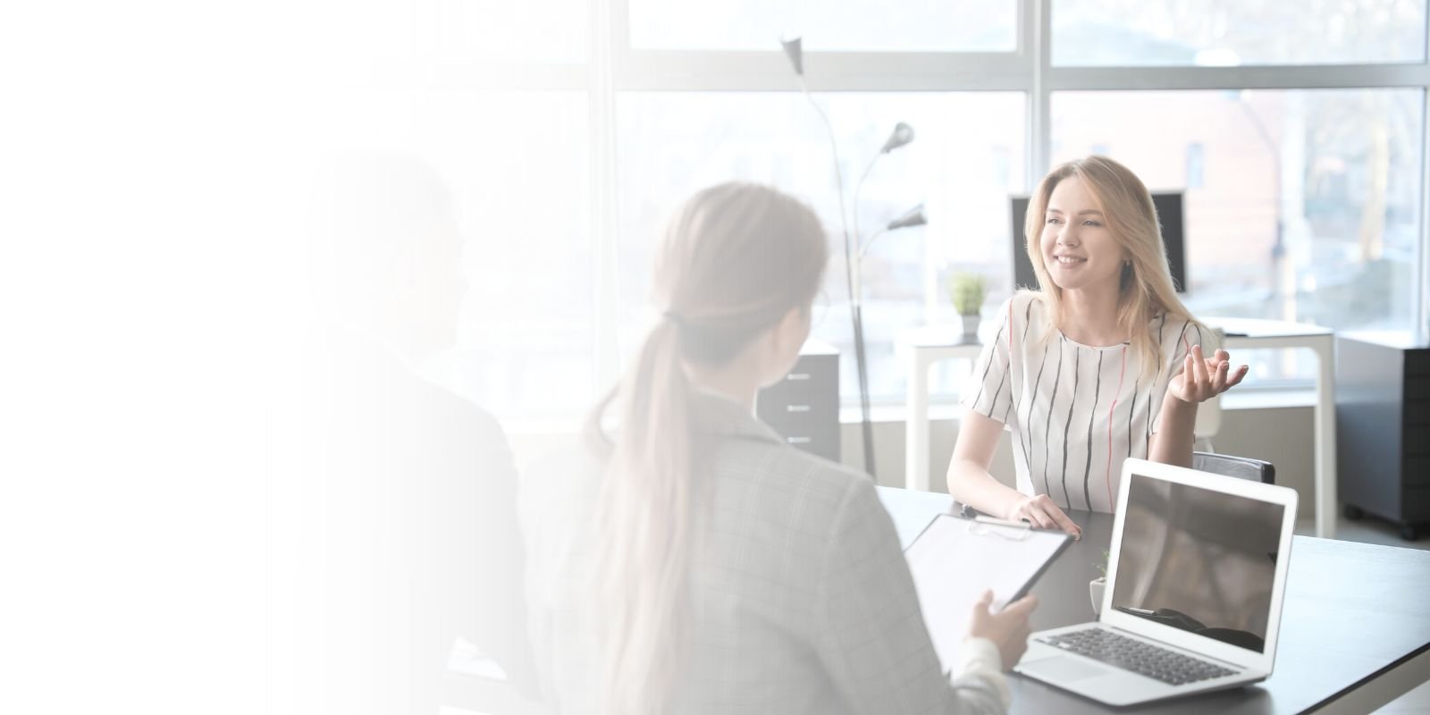 Reclutadora ejecutiva de Talentium sonriendo mientras toma notas, con una laptop que muestra una lista de candidatos pre-calificados, en una oficina de Ciudad de México.